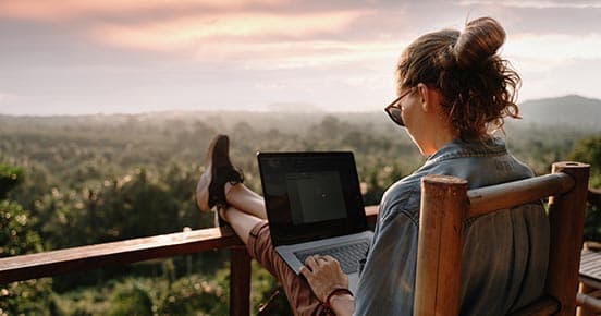 Woman with laptop.jpeg Woman with a laptop sitting on a balcony with a great view